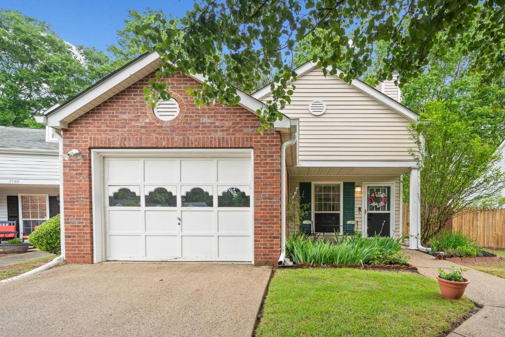 ein Backsteinhaus mit einer weißen Garagentür in der Unterkunft Charming Cottage and Loft, Home with Garage in Kennesaw in Kennesaw
