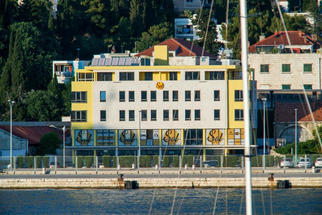 un edificio amarillo y blanco junto al agua en Hostel Sol, en Dubrovnik