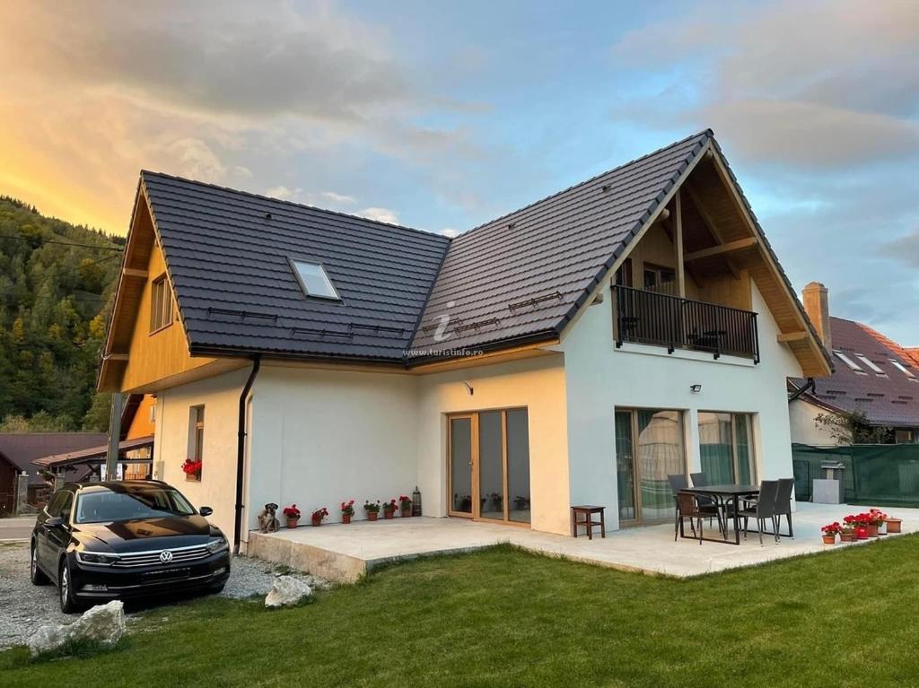 ein Haus mit einem davor geparkten Auto in der Unterkunft Pensiunea Carmen 1927 in Moieciu de Jos
