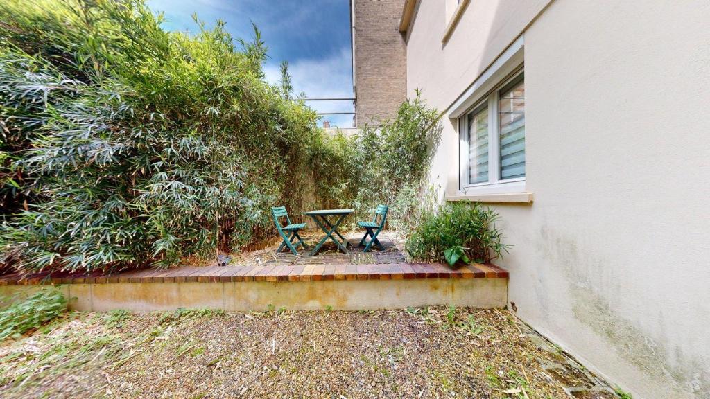 un patio avec deux chaises et une table à côté d'un bâtiment dans l'établissement Evasion de Oiseau - Lesueur, au Havre