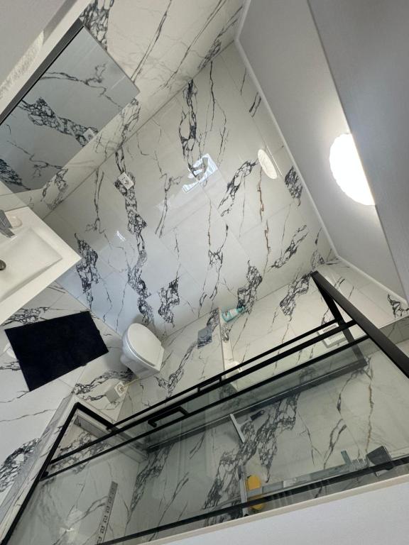 Un baño con paredes de mármol y suelo de cristal. en Mall Residence, en Văleni
