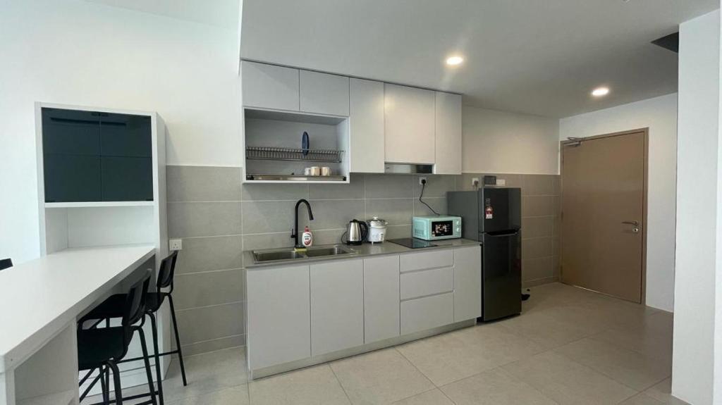 a kitchen with white cabinets and a black refrigerator at D'millenia Bangau Homestay in Kuching