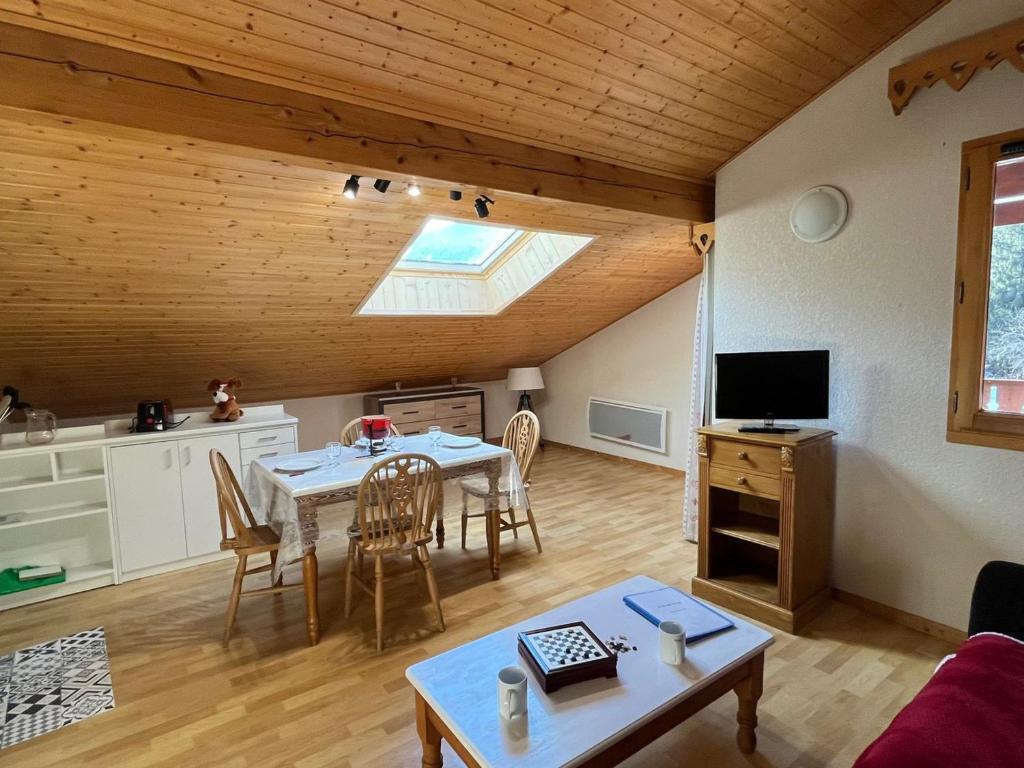 - un salon avec une table à manger et une lucarne dans l'établissement Appartement cosy avec piscine, balcon et parking - FR-1-629-124, à Samoëns