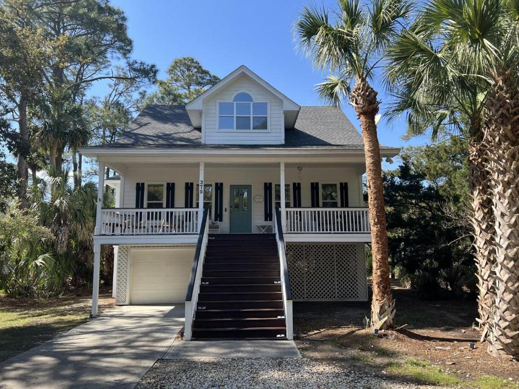 a white house with palm trees in front of it at Beautifully appointed 3-Bed, 25-Bath Home, Great Location near Beach & Club in Fripp Island
