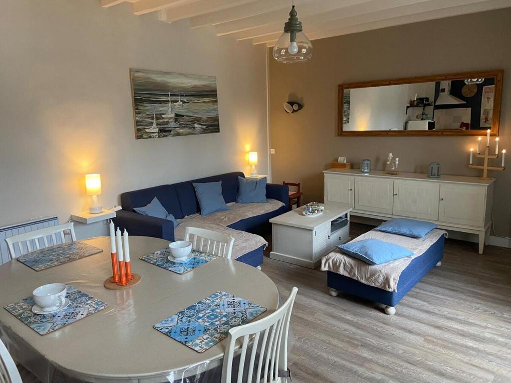 a living room with a table and a blue couch at D-Day Cottage La Maove in Grandcamp-Maisy