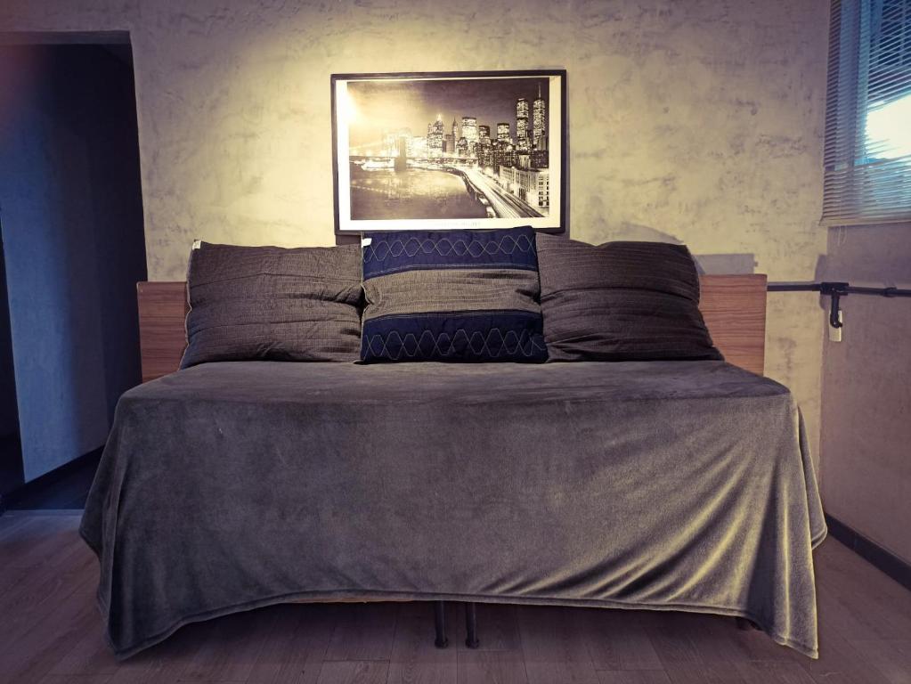 a bed in a bedroom with a picture on the wall at Apartamento 05 - Um quarto, sala e cozinha in Balneário Camboriú