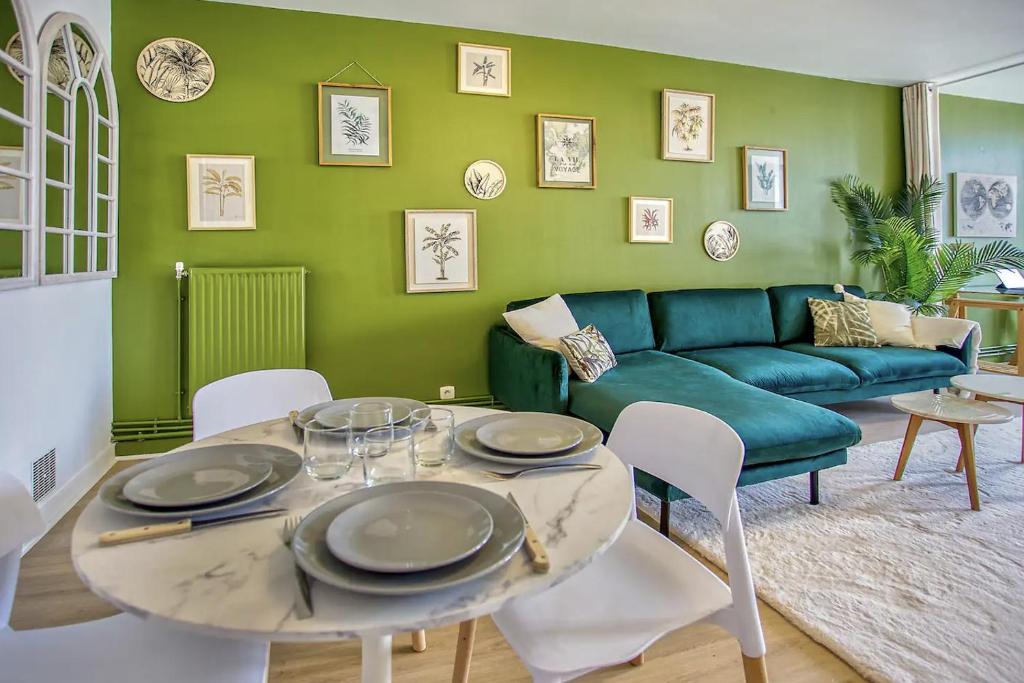 a living room with a green couch and a table and chairs at La suite végétale, spacieuse et hyper centre in Angoulême