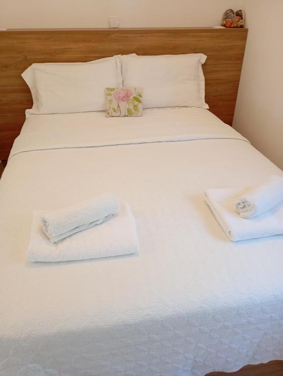 a large white bed with two towels on it at Charoula's Apartments in Syvota