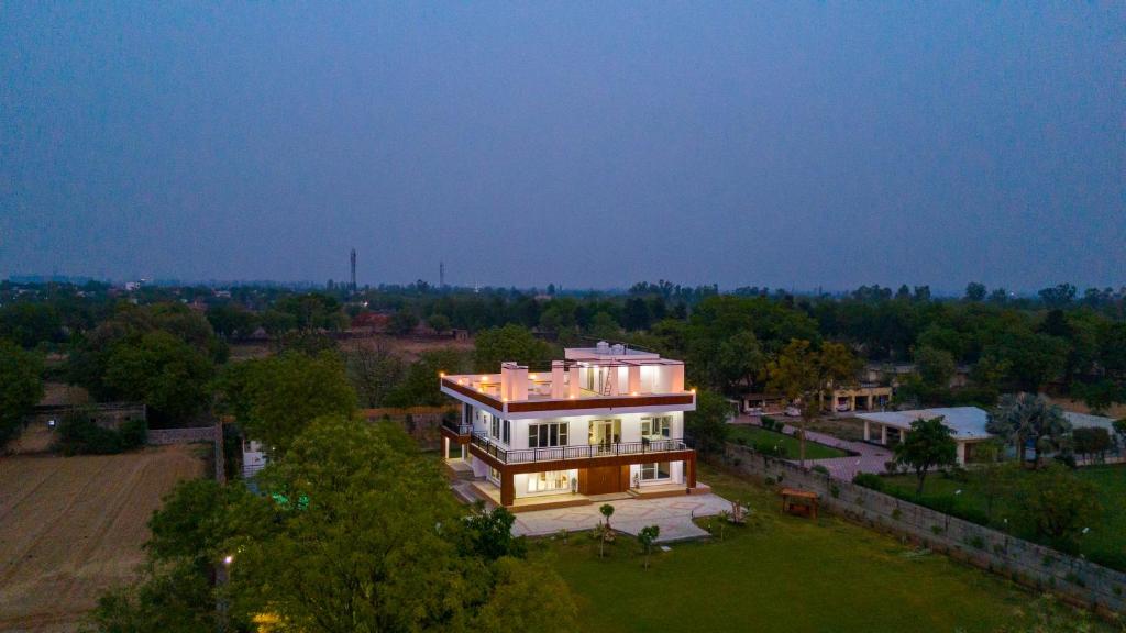 eine Luftaufnahme eines großen Hauses auf einem Feld in der Unterkunft ELIVAAS 3 BHK Amber Villa With Pvt Pool, Game Room & Studio Rooms in Dhauj