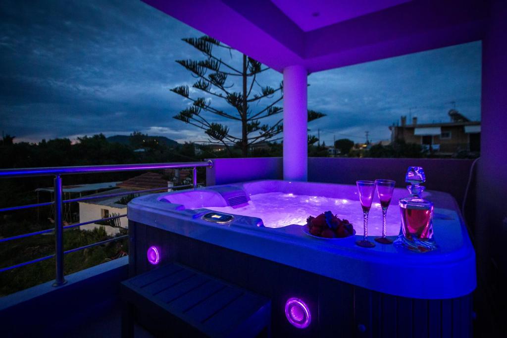 a jacuzzi tub with wine glasses and purple lights at DimArist Residence in Zakynthos