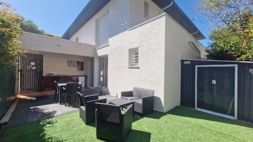 einen Garten mit Stühlen und einem Zaun und einem Haus in der Unterkunft "Villa de Jade" Maison de vacances en residence avec piscine - Clim - parking in Saint-Cyprien