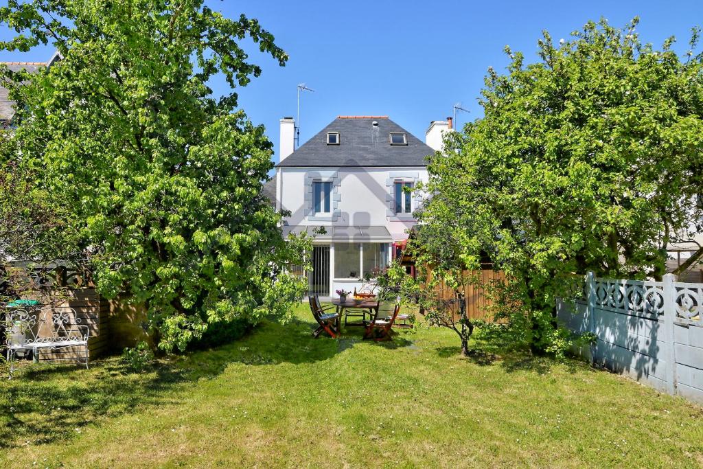 a yard with two trees and a white house at LocaLise - M26B - Les Belles Âmes - Maison rénovée avec jardin entièrement clos - place de parking sur le terrain - wifi inclus - draps inclus - animaux bienvenus in Le Guilvinec