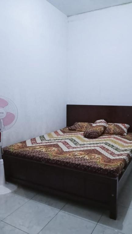 a bed with a wooden frame with a quilt on it at Homestay Rafa Borobudur in Sekatonan