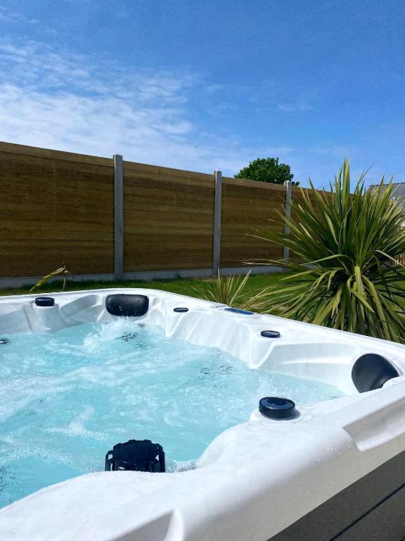 une baignoire jacuzzi dans une arrière-cour avec une clôture dans l'établissement Villa Palulova - maison 8 personnes - SPA, à Plouescat