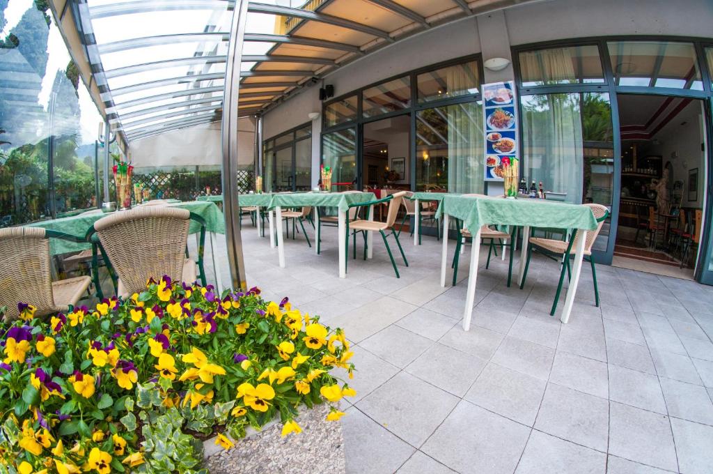 a patio with green tables and chairs and flowers at Hotel Primo in Riva del Garda