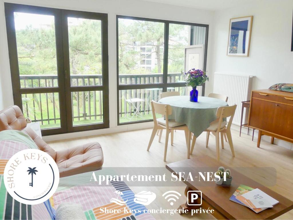 un salon avec une table, des chaises et des fenêtres dans l'établissement Appartement Tout Confort-Plage & Centre à Pied, à Seignosse