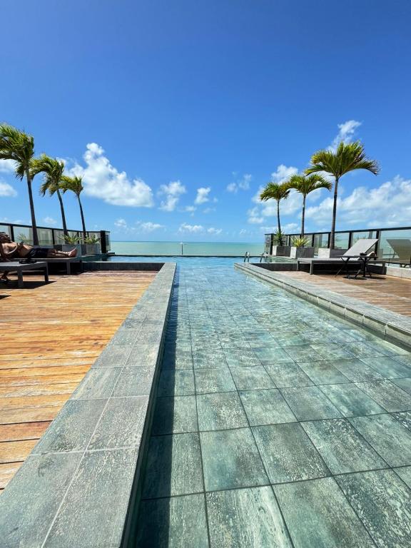 a boardwalk with palm trees and the water at SUITE PREMIUM VISTA MAr in João Pessoa