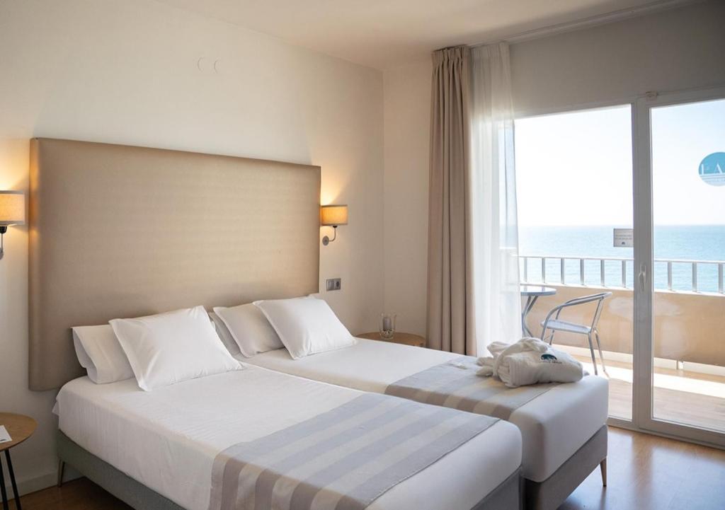 two beds in a hotel room with a view of the ocean at FAY Victoria Beach in Rincón de la Victoria
