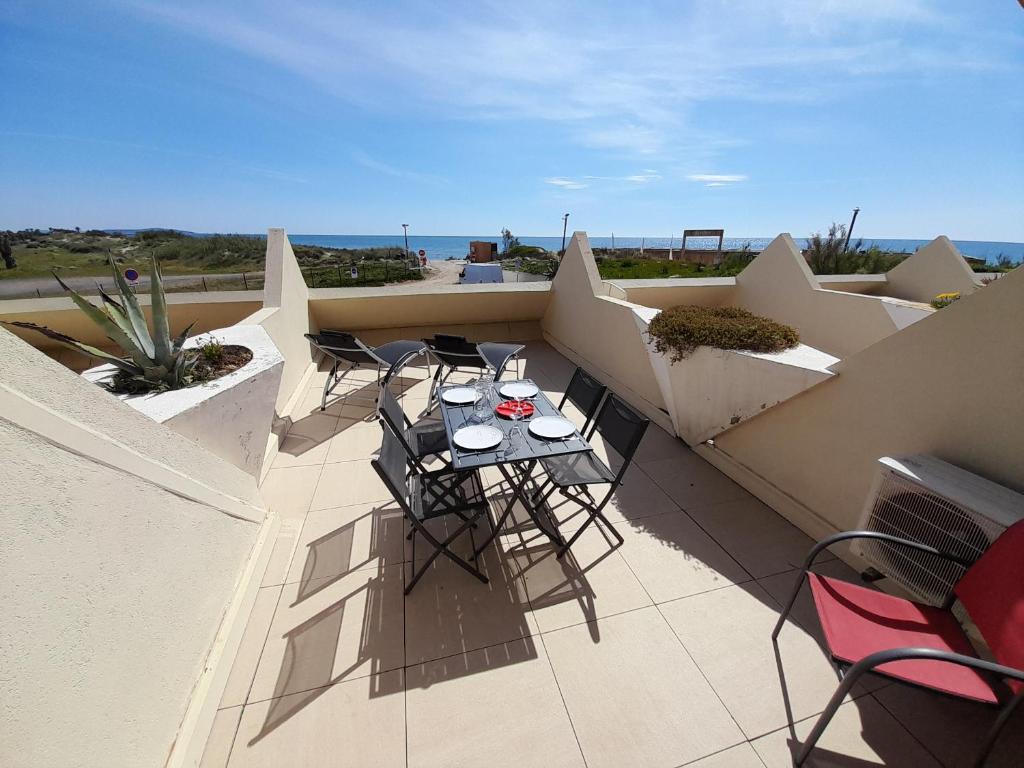 un patio avec tables et chaises sur un balcon dans l'établissement Appartement Village Naturiste Paradoxe, au Cap d'Agde