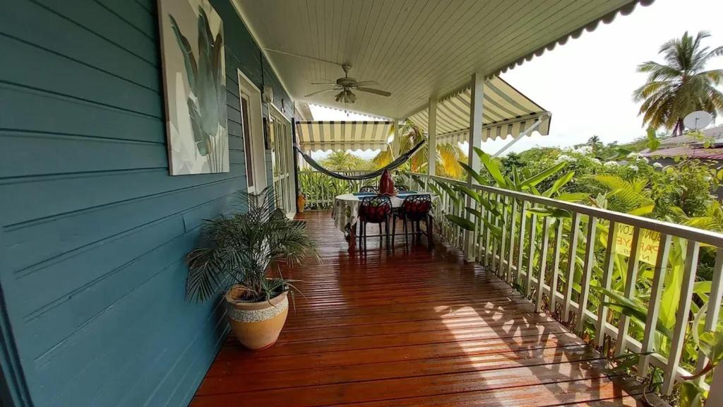 un porche d'une maison bleue avec une table dessus dans l'établissement Charmant bungalow à Bouillante avec vue sur la mer, à Bouillante