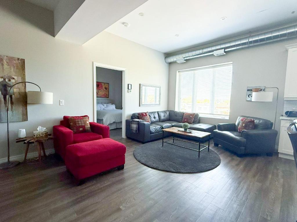 a living room with two couches and a red chair at Contemporary East Loft in Historic Niagara in Niagara on the Lake