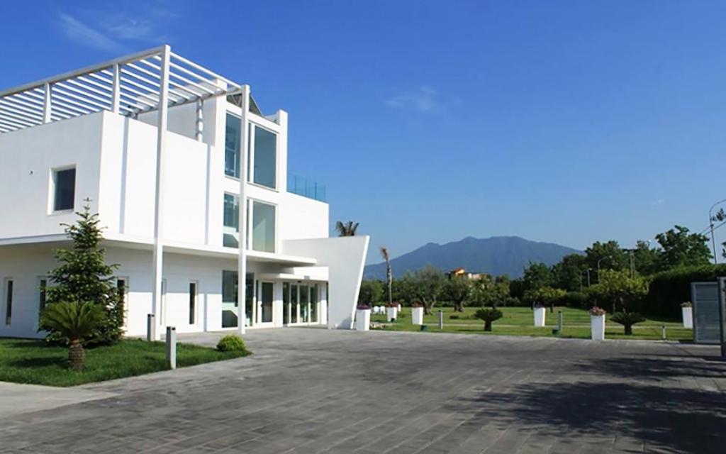 ein weißes Gebäude mit einer Einfahrt davor in der Unterkunft Pietrabianca Exclusive Resort in Pomigliano dʼArco