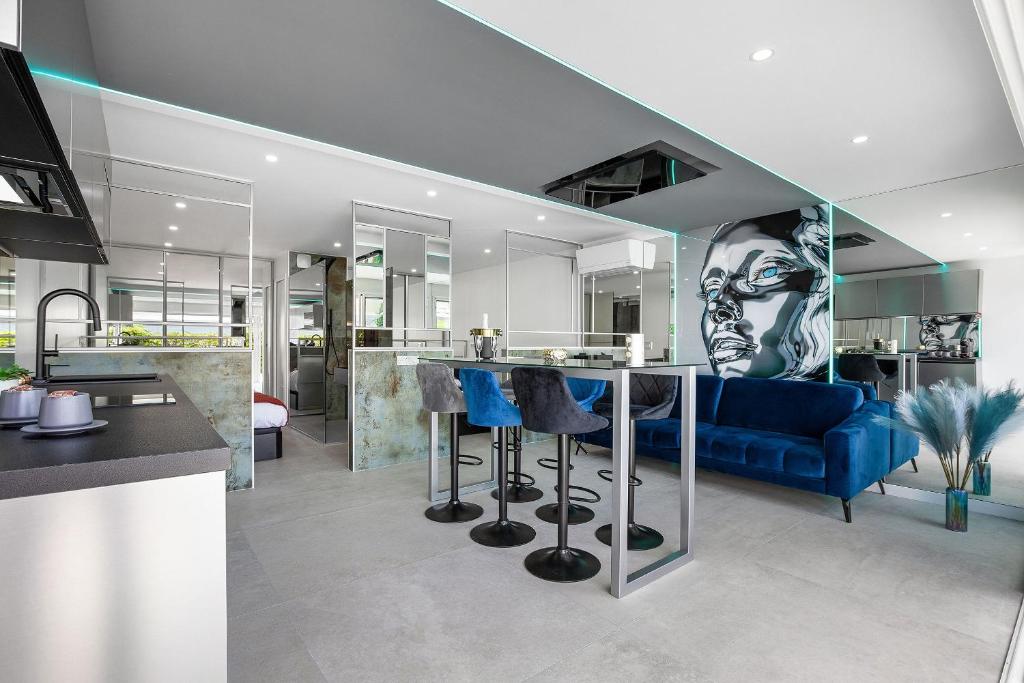 Il comprend une cuisine et un salon doté d'un canapé bleu. dans l'établissement Village Naturiste R4N - La Villa Double Game Luxe, au Cap d'Agde