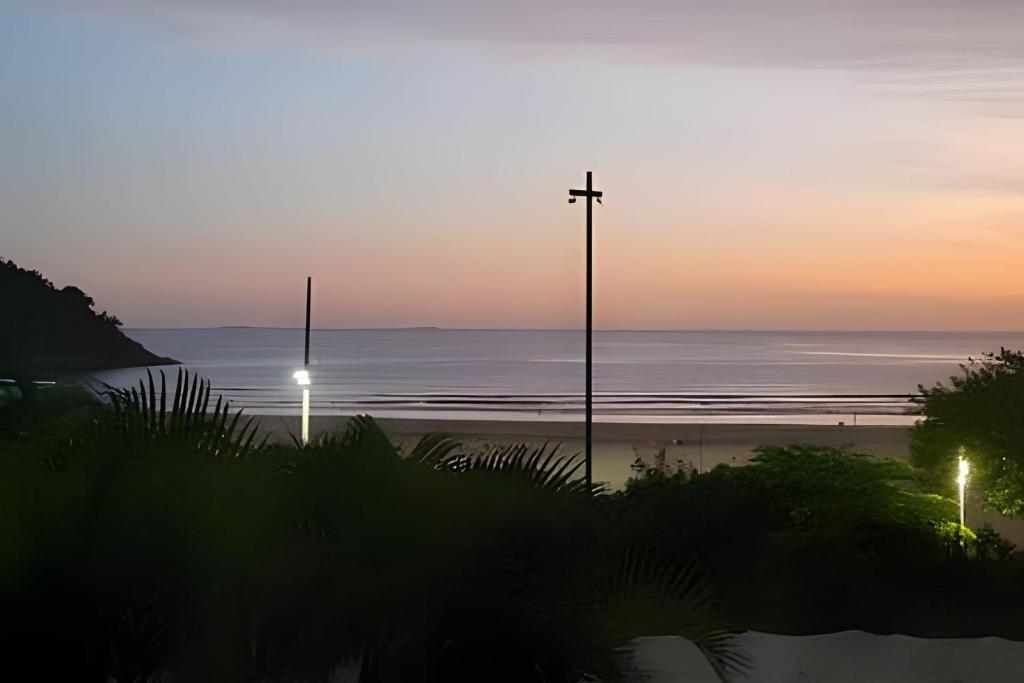 a cross on a beach with the ocean at sunset at Studio à Beira-mar - Santos in Santos