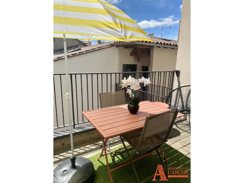 une table et des chaises sur un balcon avec un parasol dans l'établissement Appartement avec Terrasse privée sur les toits de Toulouse, à Toulouse