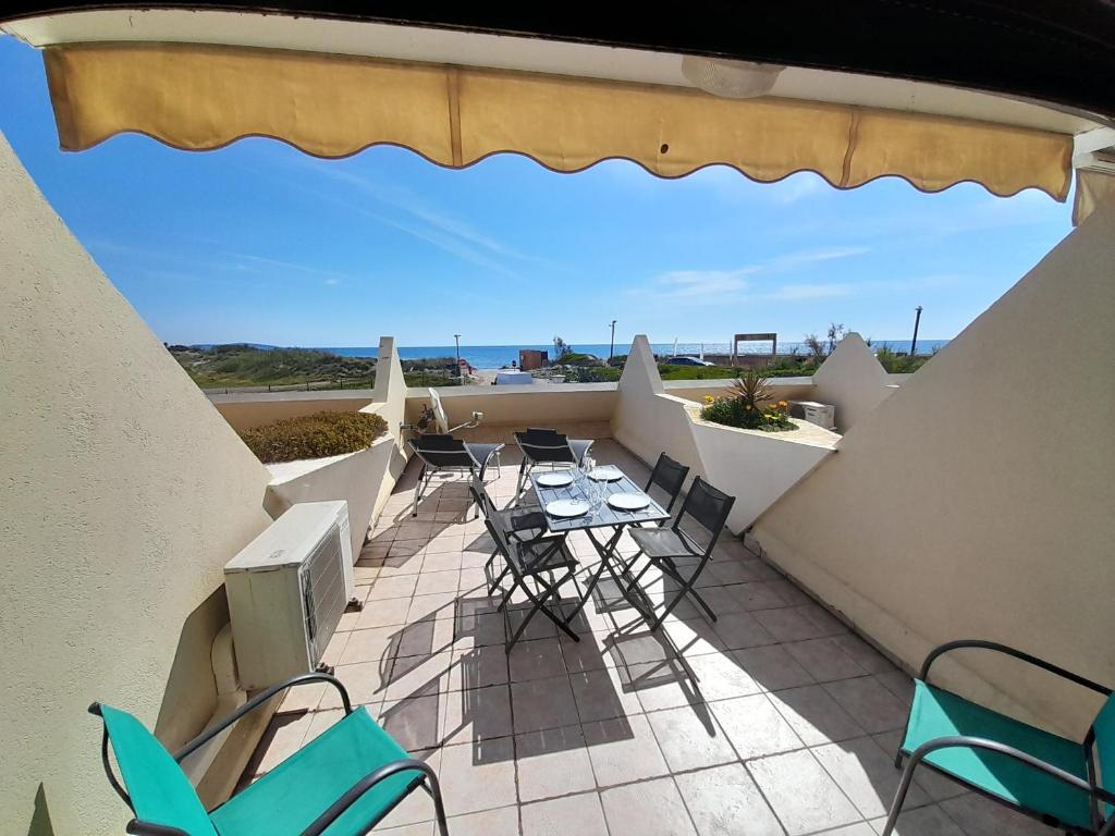 un balcon avec une table et des chaises et l'océan dans l'établissement Appartement Village Naturiste Paradoxia, au Cap d'Agde