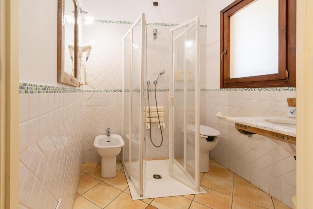 a bathroom with a shower and a toilet and a sink at Porto Giunco Residence in Villasimius