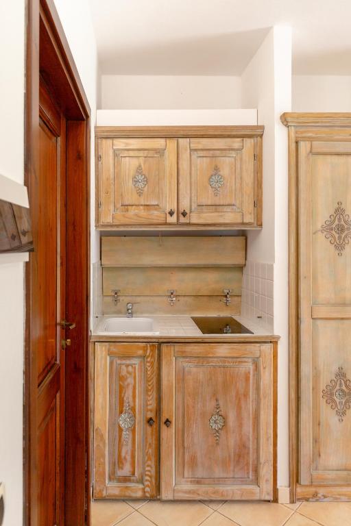 a kitchen with wooden cabinets and a sink at Porto Giunco Residence in Villasimius