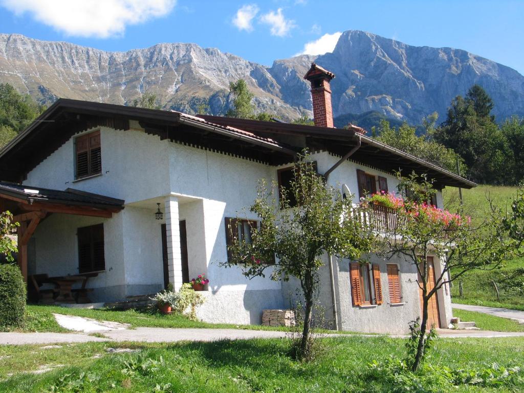 a small white house with mountains in the background at Tourist Farm Žvanč in Kobarid