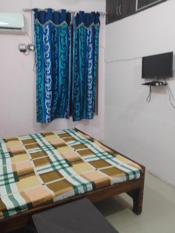 a bed in a room with blue curtains and a tv at Ashiyana Upvan in Lucknow