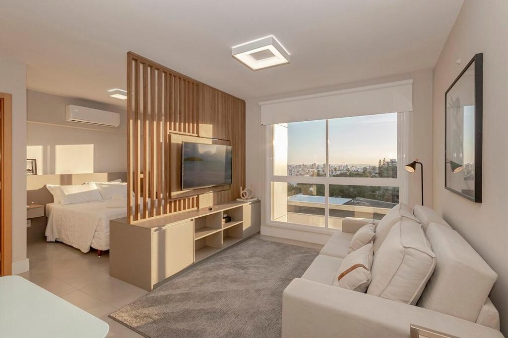 Una sala de estar con un sofá, una cama y un televisor. en 304 Axis Home Loft Alto Padrão, en Porto Alegre