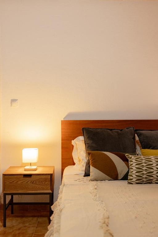 a bed with a night stand with a lamp on it at Solar de Lalém in Maia