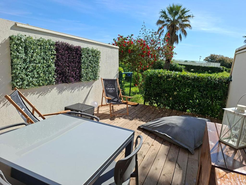 un patio avec une table et des chaises et une clôture dans l'établissement Résidence Les Goelettes Appartement avec terrasse - Clim - Wifi - parking - Piscine - Front de mer, à Saint Cyprien Plage