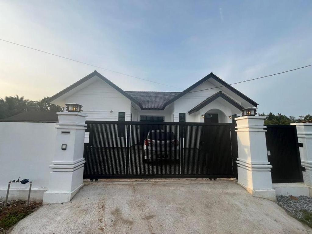 Bukit PayongHusna WhiteStay的一栋白色的房子，大门后面有一辆汽车