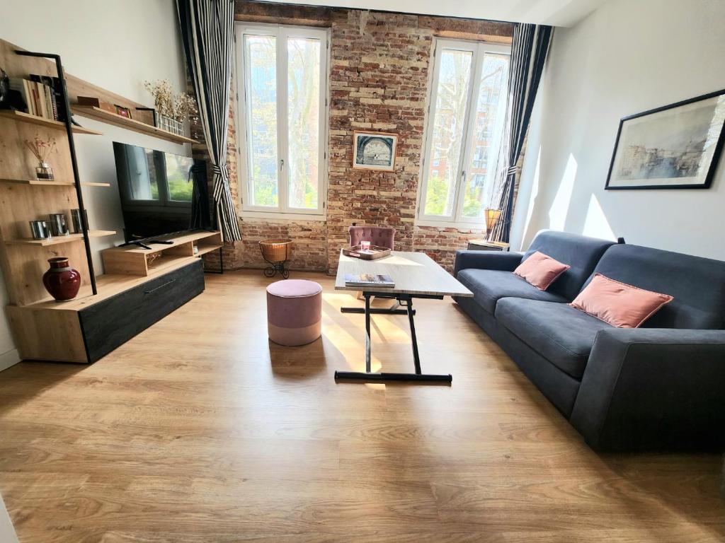 un salon avec un canapé bleu et une table dans l'établissement Luxine One - Appartement 4 pers - Entre Canal et Gare Matabiau, à Toulouse