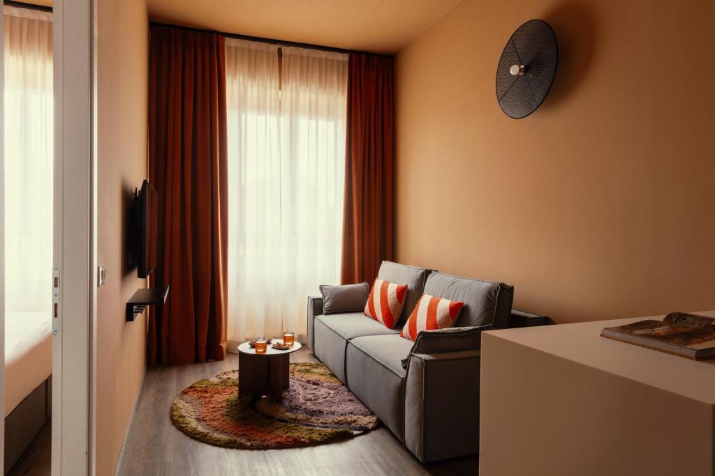 a living room with a couch and a clock on the wall at Bob W Ticinese in Milan