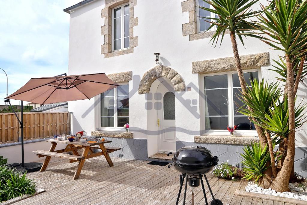 a bbq grill on a wooden deck in front of a house at LocaLise - M5 - Maison de vacances sur le port de Lechiagat - terrasse entièrement close - Wifi inclus - Draps inclus - Animaux bienvenus in Tréffiagat