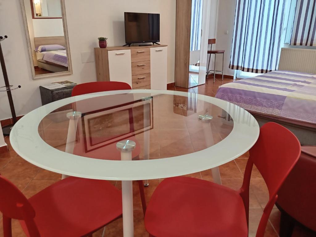 a room with a glass table and red chairs at Apartments Košević in Osijek
