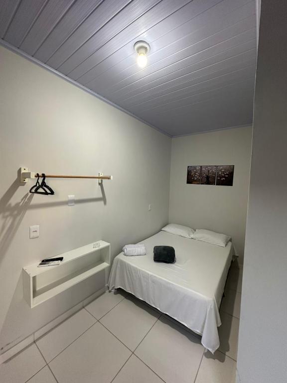 a bedroom with a bed with a black bag on it at Hotel São Miguel in Posse