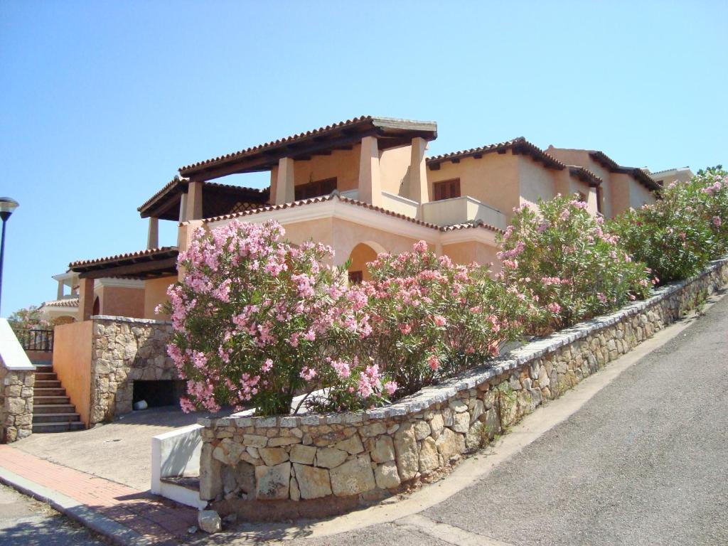 una casa con flores rosas frente a una pared de piedra en Case Vacanza Rosa, en Porto San Paolo