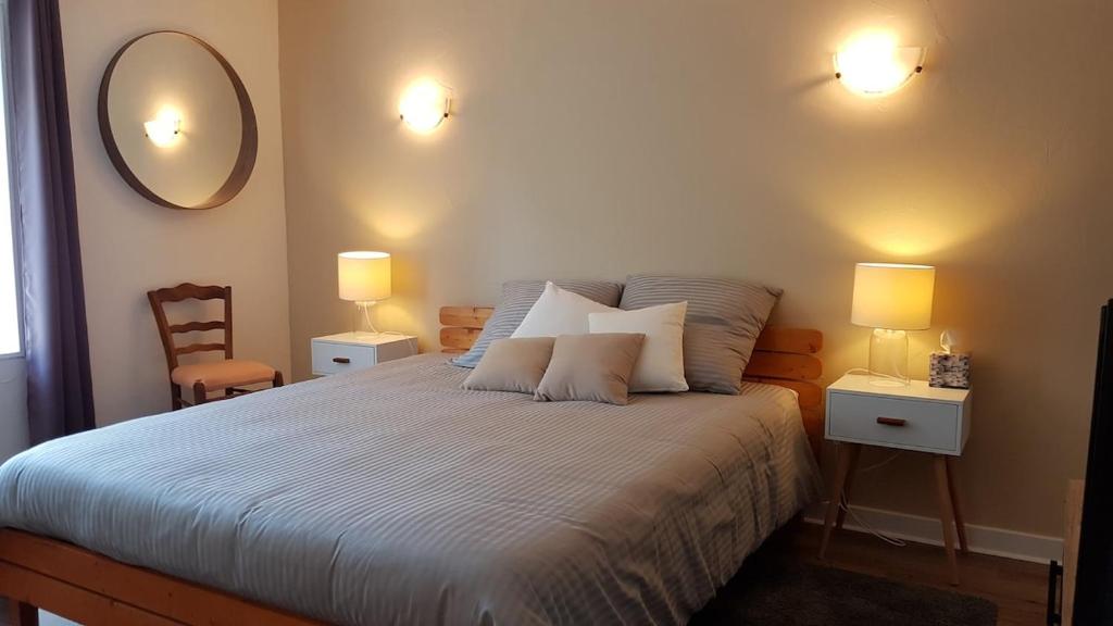 a bedroom with a bed with two lamps and a mirror at Studio proche Chaine des Puys, SDB privée, kitchenette in Saint-Genès-Champanelle