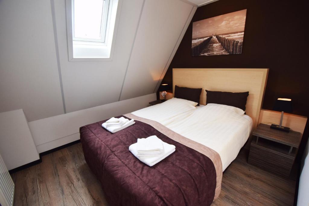 een slaapkamer met een bed met twee handdoeken erop bij Hotel Noordzee in Domburg