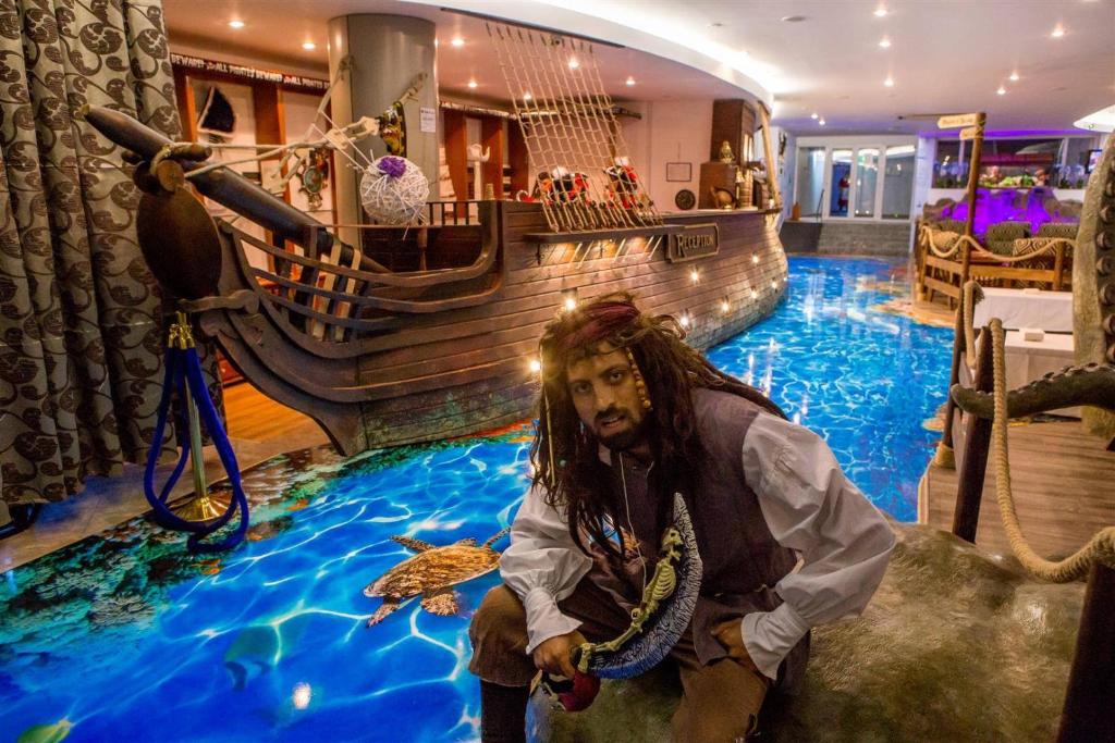 Un uomo seduto di fronte a una nave pirata in una stanza di Pirates Resort a Mamaia