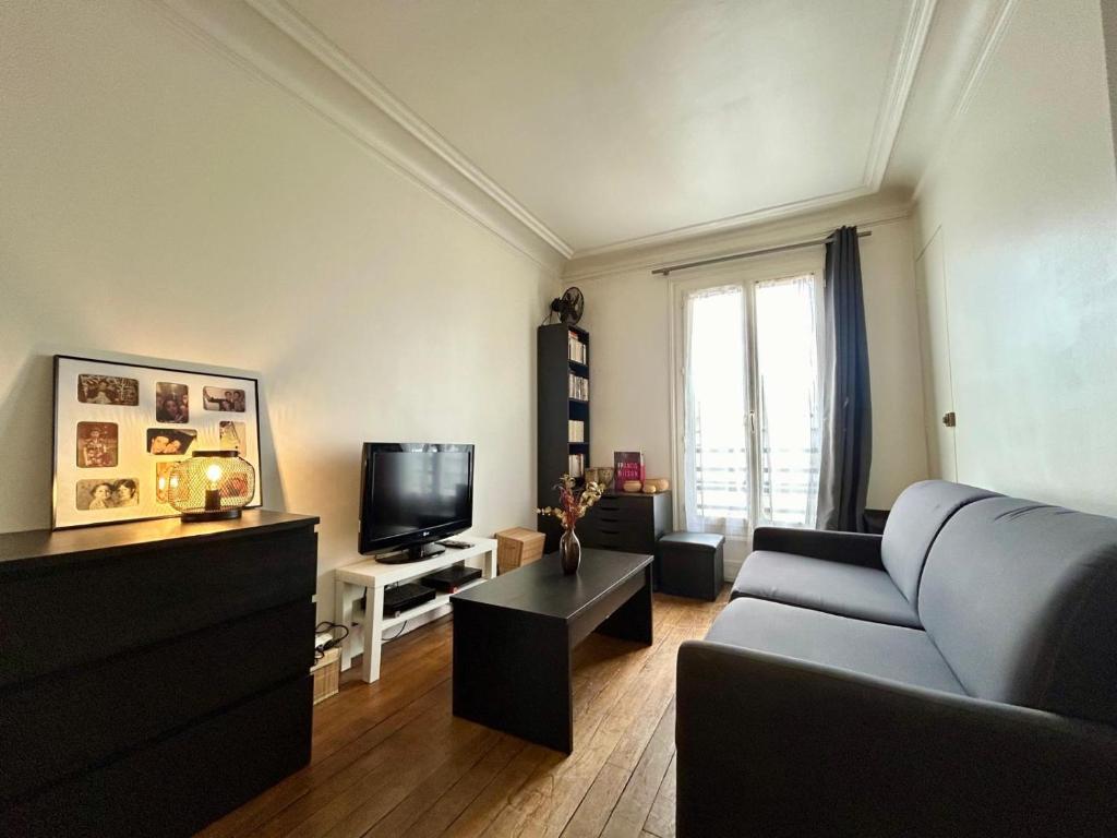 un salon avec un canapé et une télévision dans l'établissement Le Jaures - Centre ville Metro 3, à Levallois-Perret
