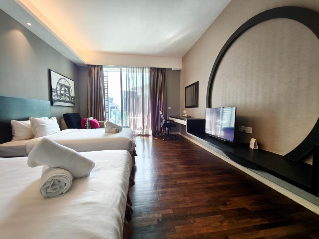 a hotel room with two beds and a flat screen tv at The Shore Residences by Amanjiwa in Melaka
