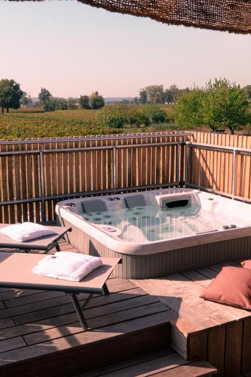 un bain à remous sur une terrasse avec une clôture dans l'établissement Au Chai Bigaroux Saint-Emilion, à Saint-Sulpice-de-Faleyrens